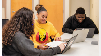Three high school students look at laptops