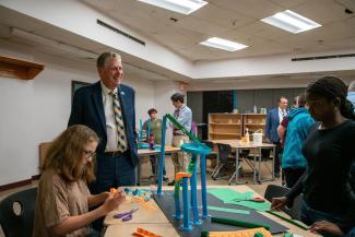 Governor Dan McKee stands with students at a desk participating in summer programming
