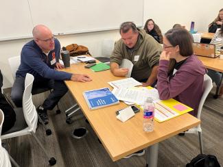 Teachers sitting at a table and reviewing curriculum materials.