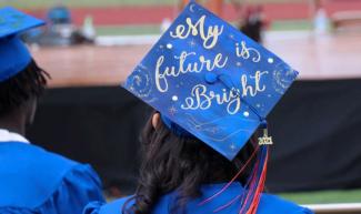 A girl wearing a blue graduation cap that says "My future is bright."