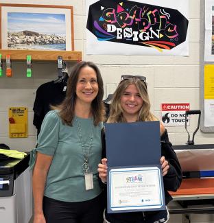 This is a picture of the 2026 STEAM Logo Design Contest Winner Kaitlyn Charette and her Graphic Design Teacher Donna Caster